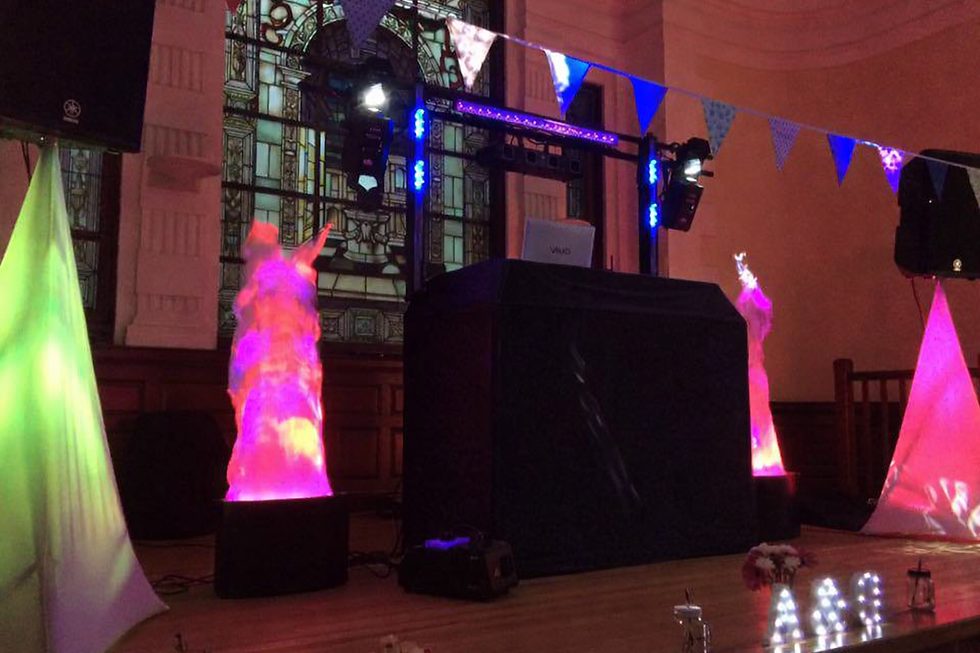JMD Entertainments DJ set-up with black booth, moving lights and pink and green uplighting