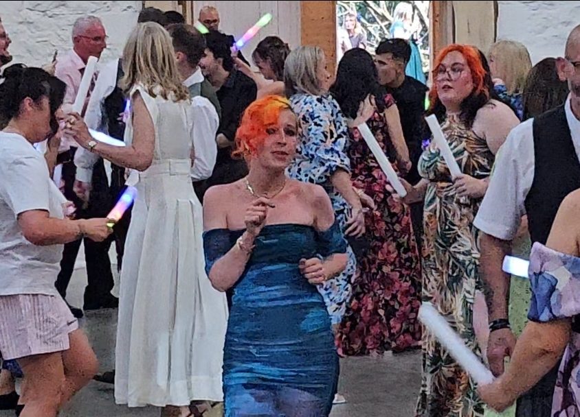 Guests holding glow sticks on the dancefloor during an evening reception